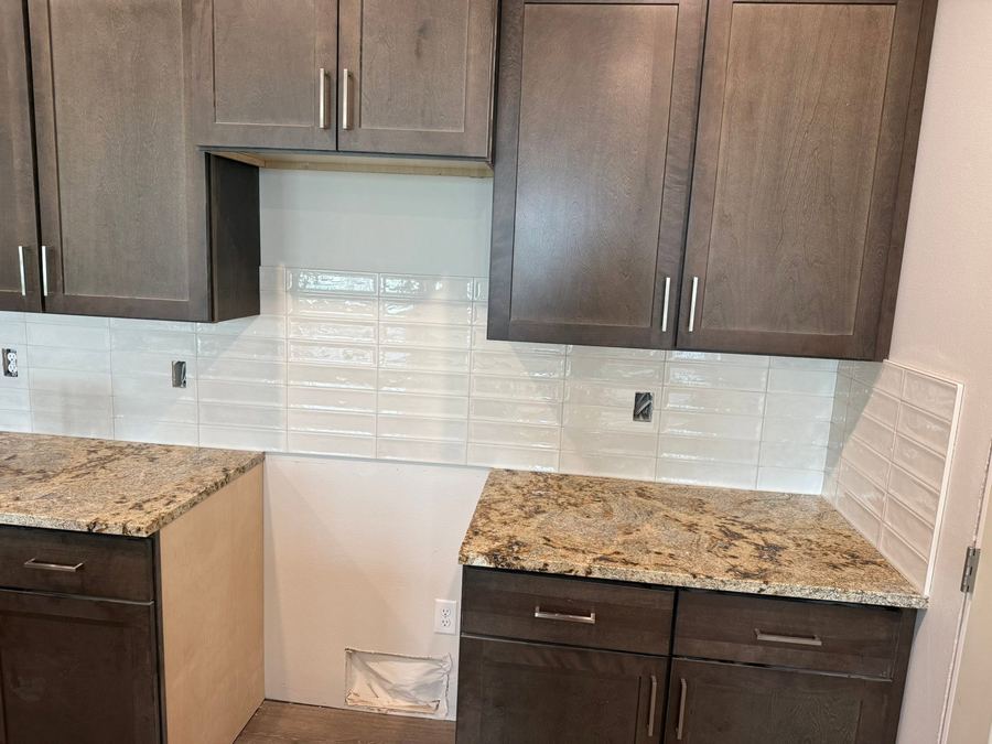 Kitchen backsplash tiled in glossy white stacked tile, cut cleanly around the outlets